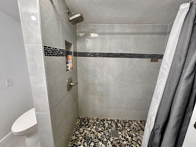 bathroom with toilet, a textured ceiling, and a shower with shower curtain