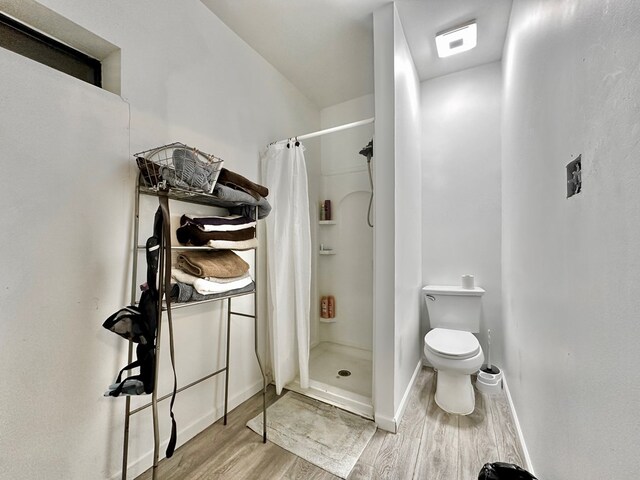 bathroom featuring toilet, hardwood / wood-style floors, and a shower with curtain