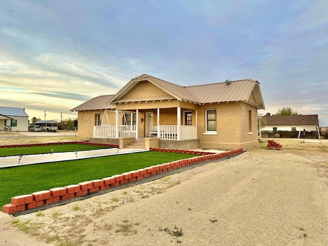 view of front of property with covered porch and a yard