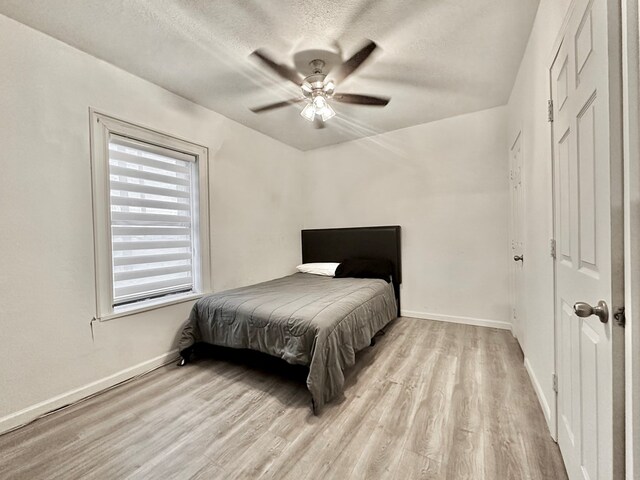 bedroom featuring ceiling fan, a textured ceiling, and light wood-type flooring