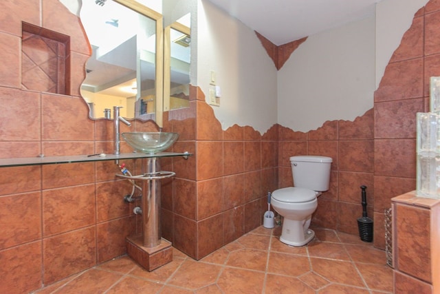 bathroom featuring sink, tile patterned flooring, tile walls, and toilet