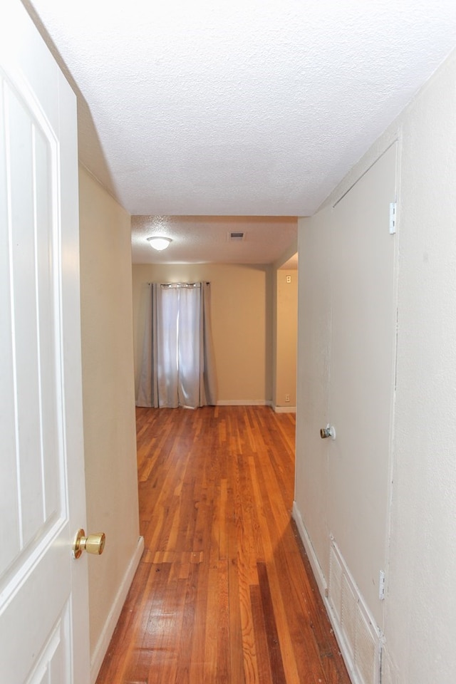 hall with a textured ceiling and hardwood / wood-style floors