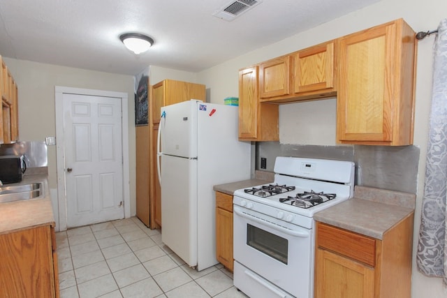 kitchen featuring white appliances, light brown cabinetry, and light tile patterned floors