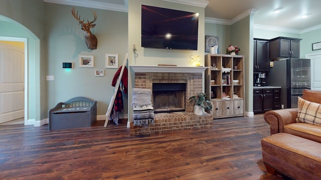 living area with dark wood-style floors, ornamental molding, a brick fireplace, and baseboards