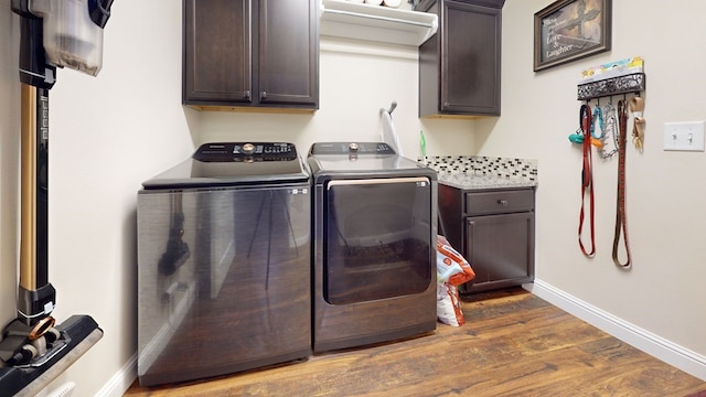 washroom with cabinet space, baseboards, washer and clothes dryer, and dark wood-type flooring