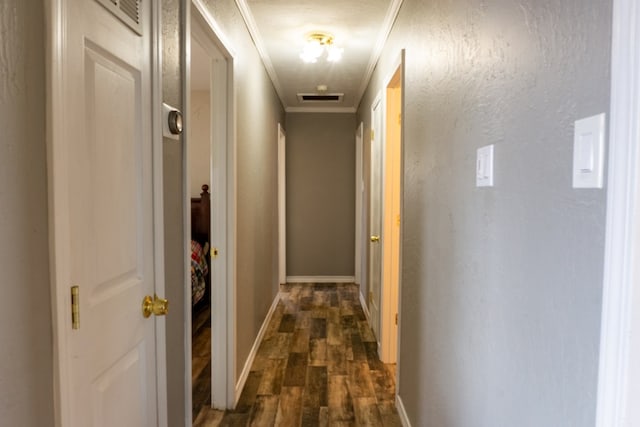 corridor with ornamental molding, dark wood-style flooring, visible vents, and baseboards