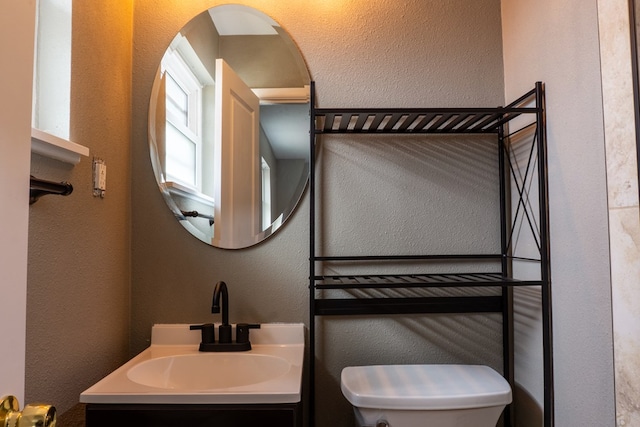 bathroom featuring a textured wall, vanity, and toilet