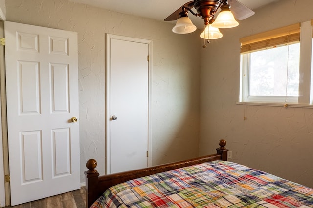 bedroom featuring a ceiling fan, wood finished floors, and a textured wall