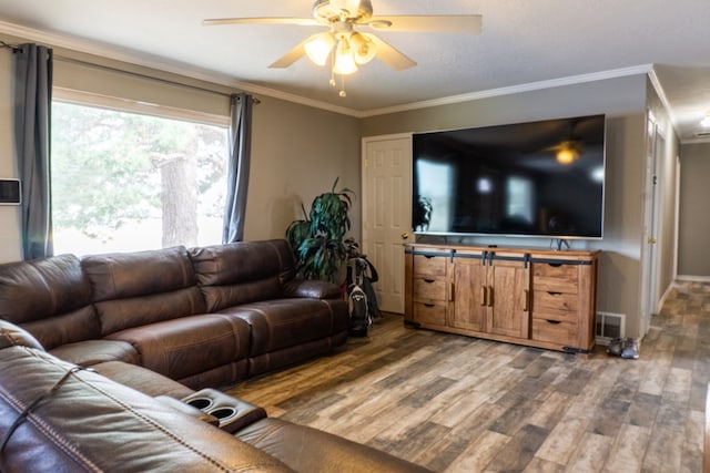 living area with ornamental molding, a ceiling fan, visible vents, and wood finished floors