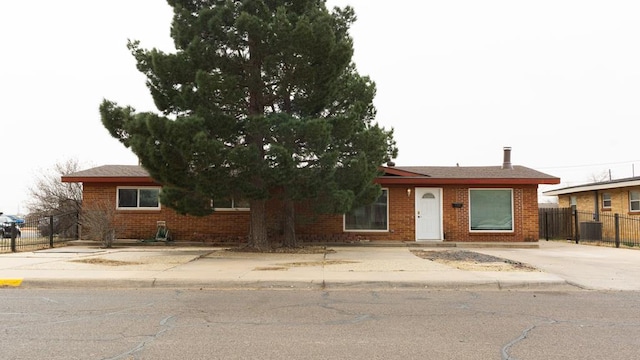 ranch-style house featuring brick siding, cooling unit, and fence