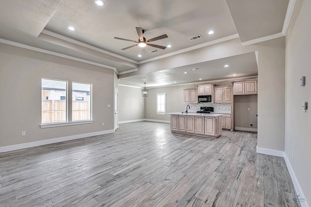 kitchen featuring ceiling fan with notable chandelier, an island with sink, light hardwood / wood-style floors, and light brown cabinets