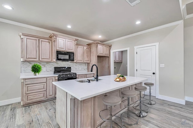 kitchen featuring black appliances, light hardwood / wood-style flooring, sink, and a center island with sink