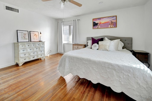 bedroom with light wood finished floors, baseboards, visible vents, and a ceiling fan