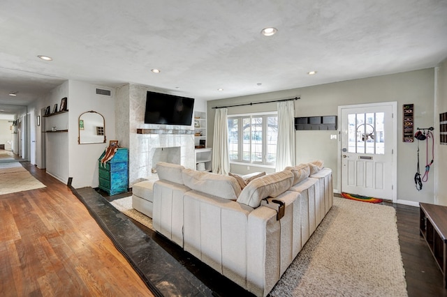 living area with baseboards, visible vents, a premium fireplace, wood finished floors, and recessed lighting