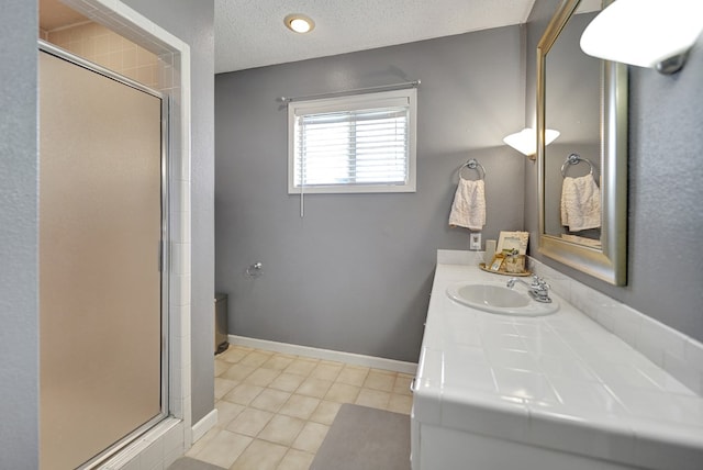 full bathroom with a stall shower, baseboards, tile patterned floors, a textured ceiling, and vanity