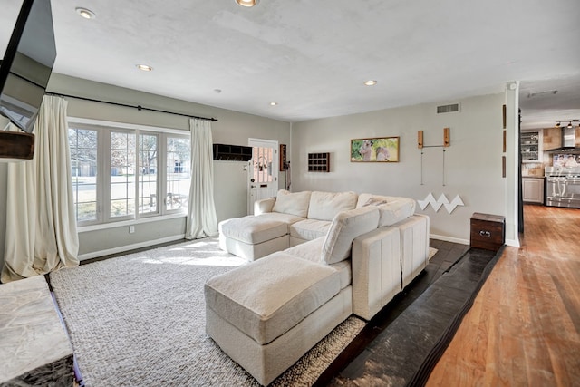 living room featuring recessed lighting, visible vents, baseboards, and wood finished floors