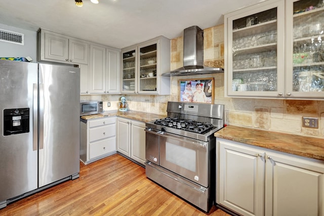 kitchen with visible vents, decorative backsplash, light wood-style floors, appliances with stainless steel finishes, and wall chimney range hood