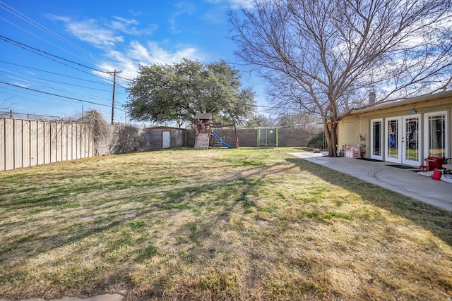 view of yard featuring a fenced backyard, a patio, a playground, and french doors