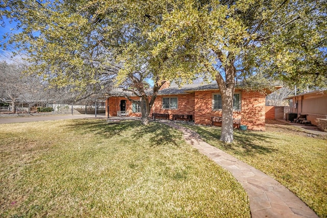 view of front facade featuring brick siding, fence, and a front lawn