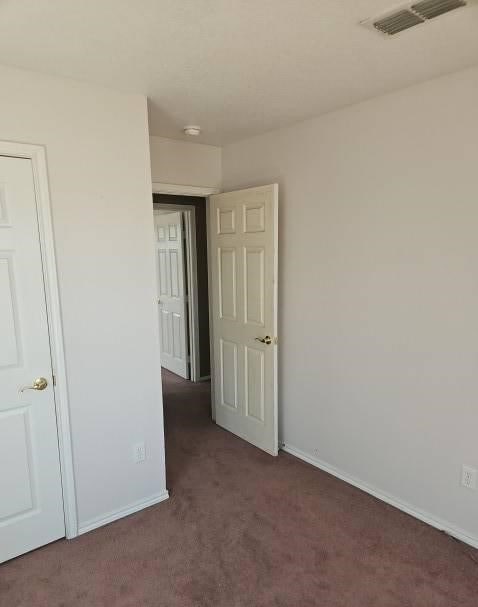 unfurnished bedroom with carpet floors, baseboards, and visible vents