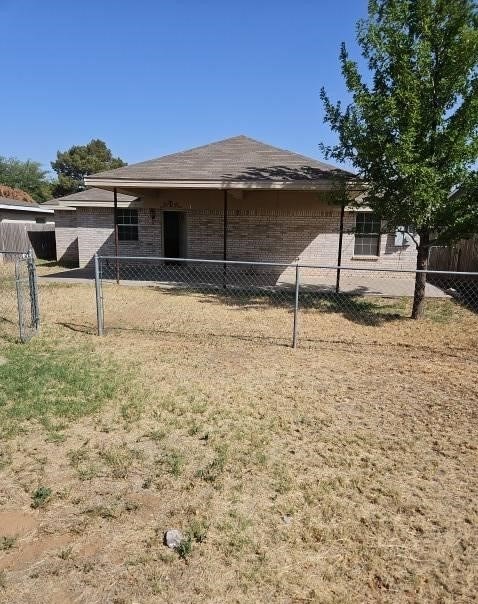 rear view of property featuring brick siding and fence