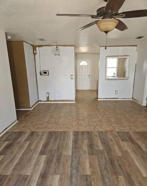 spare room with baseboards, ceiling fan, a textured ceiling, and wood finished floors