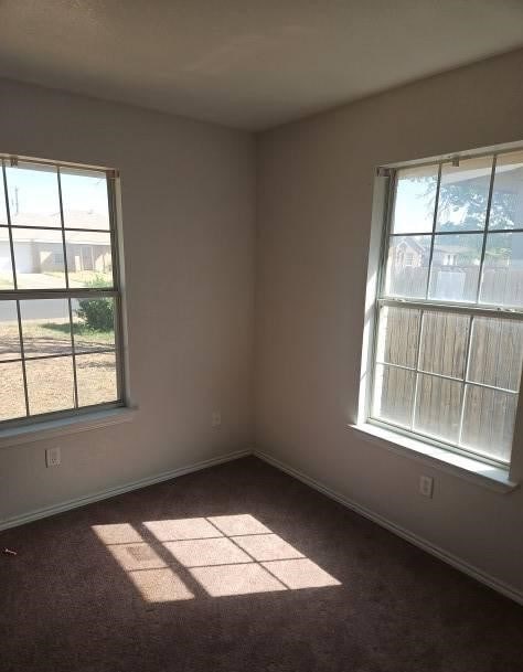 spare room featuring carpet floors and baseboards