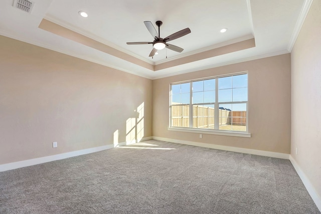 carpeted empty room featuring ceiling fan, crown molding, and a tray ceiling