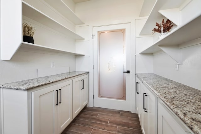 kitchen featuring dark hardwood / wood-style floors, light stone countertops, and white cabinetry