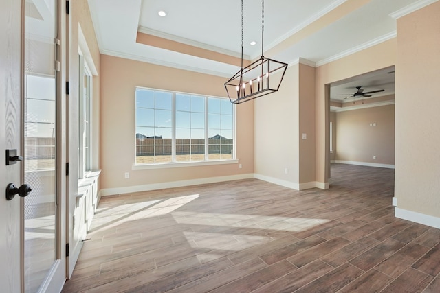 unfurnished dining area with hardwood / wood-style floors, a tray ceiling, and crown molding