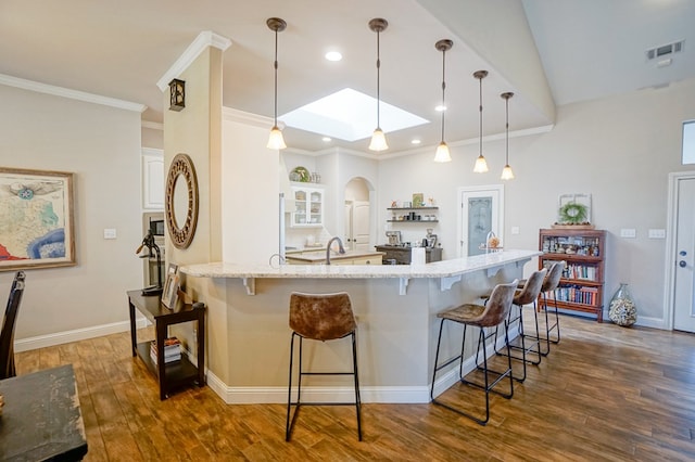 kitchen with white cabinetry, visible vents, a kitchen breakfast bar, and wood finished floors