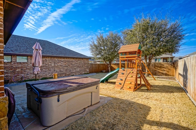 view of playground featuring a fenced backyard and a hot tub