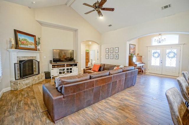 living area with visible vents, wood finished floors, a fireplace, high vaulted ceiling, and beam ceiling