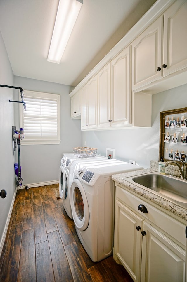 clothes washing area featuring dark wood finished floors, cabinet space, a sink, washer and dryer, and baseboards