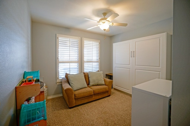 interior space with a ceiling fan, light carpet, and baseboards