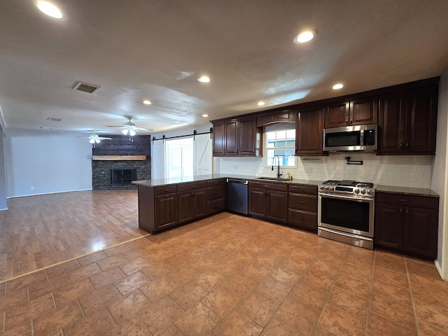 kitchen featuring visible vents, a sink, a barn door, appliances with stainless steel finishes, and decorative backsplash