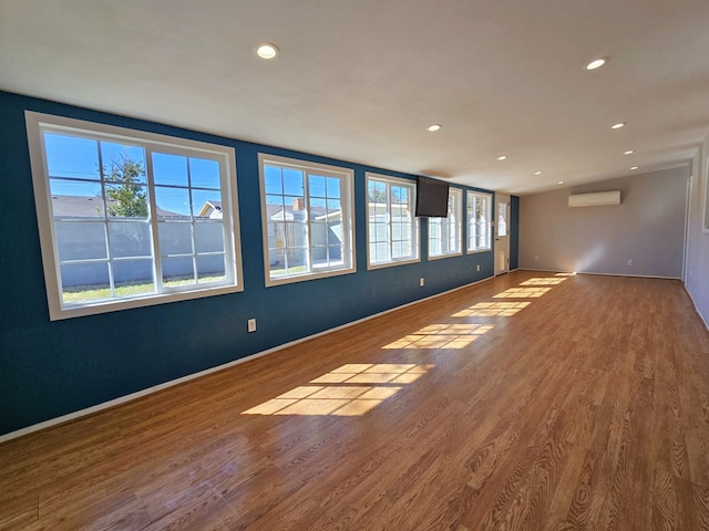 spare room with recessed lighting, wood finished floors, baseboards, and a wall mounted AC