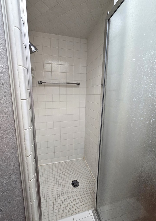 full bathroom with a textured wall and a stall shower