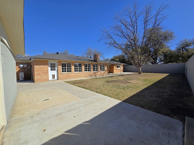 exterior space featuring a lawn, a fenced backyard, brick siding, solar panels, and a chimney