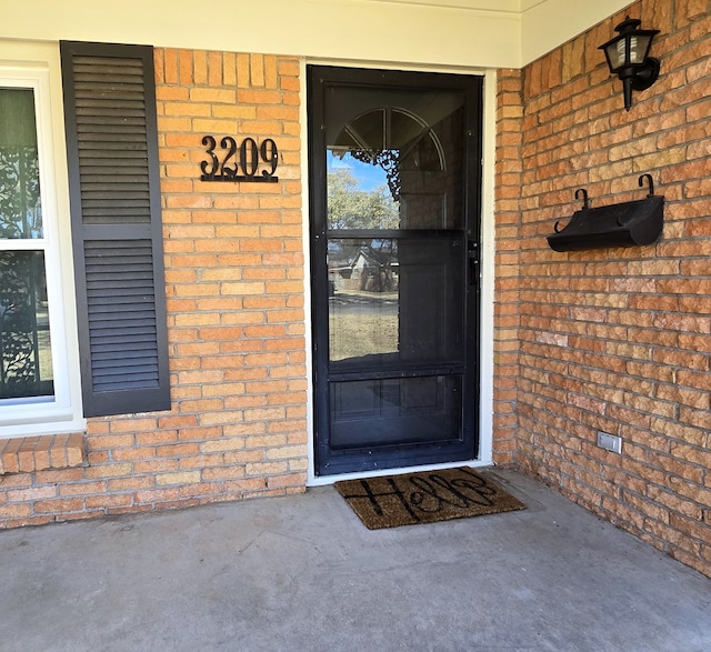 entrance to property featuring brick siding