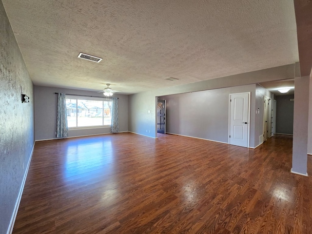 spare room with visible vents, a textured ceiling, wood finished floors, baseboards, and ceiling fan