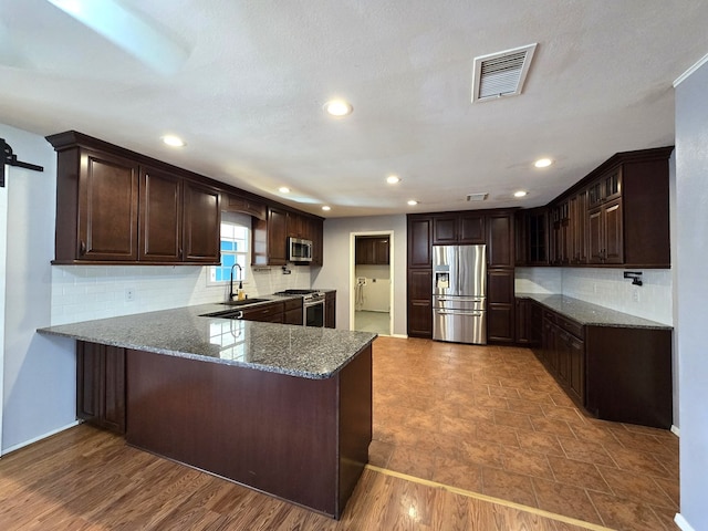 kitchen with dark brown cabinetry, visible vents, appliances with stainless steel finishes, and a peninsula