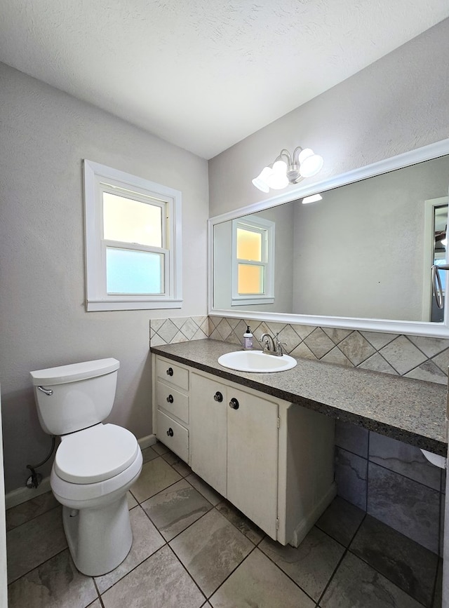 half bath featuring backsplash, toilet, and vanity