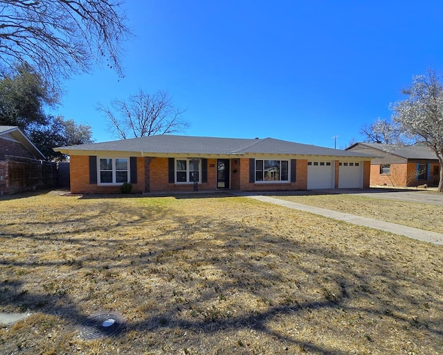 ranch-style house featuring a front yard, fence, driveway, an attached garage, and brick siding