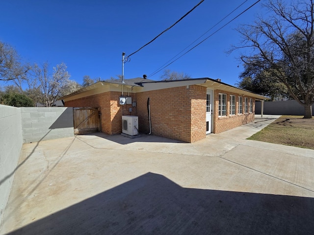 back of house with a gate, fence, ac unit, a patio area, and brick siding