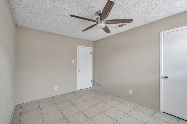 spare room with light tile patterned flooring, visible vents, a textured ceiling, and ceiling fan