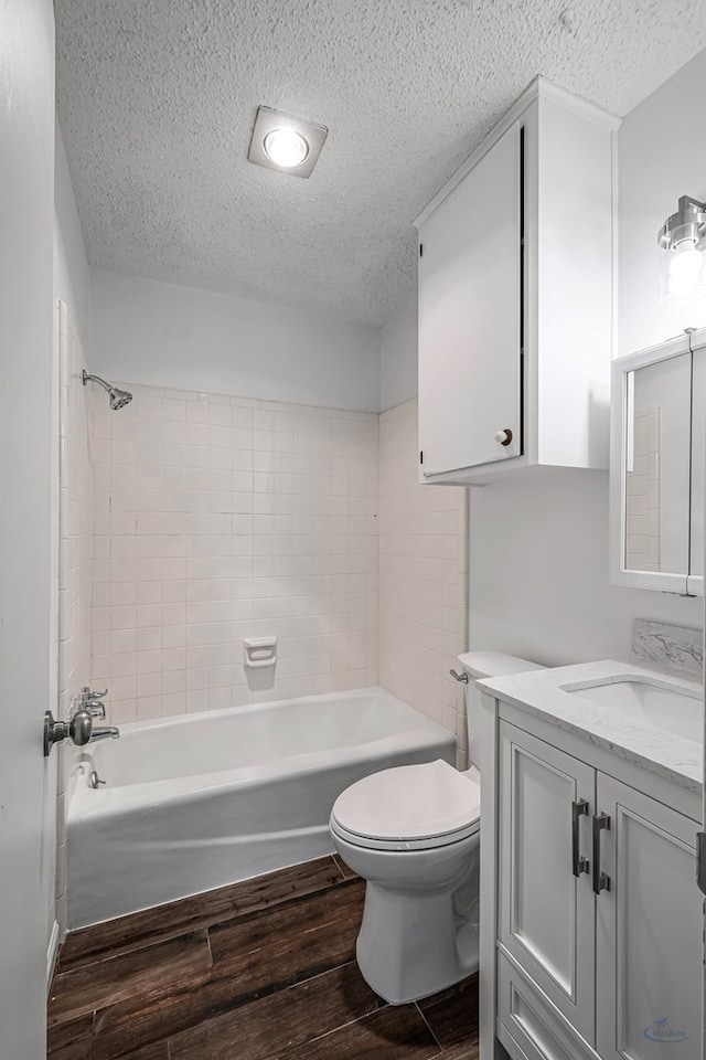 bathroom with toilet, wood finished floors, vanity, and a textured ceiling