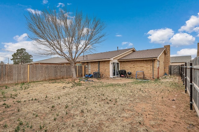 back of property with cooling unit, brick siding, and a fenced backyard