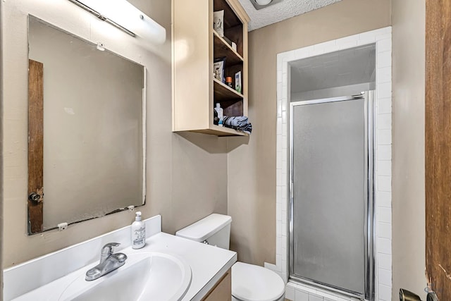 bathroom with a shower stall, a textured ceiling, toilet, and vanity