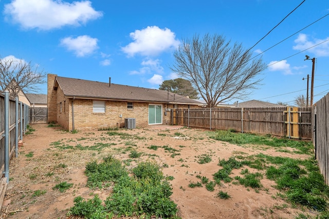 back of house with central AC unit, a fenced backyard, and brick siding